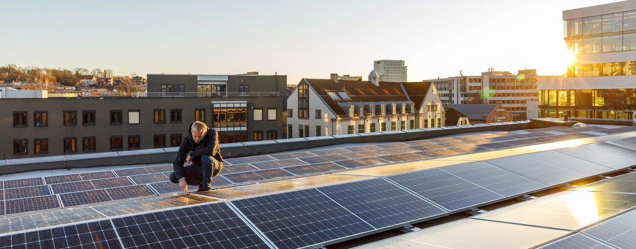 Mann på tak med solcellepanel